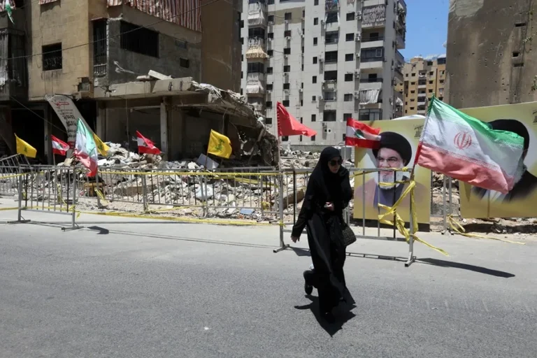 Imagen de archivo de junio de 2025 donde una mujer camina por una calle de Beirut, en medio de banderas e imágenes de Hezbolá. EFE